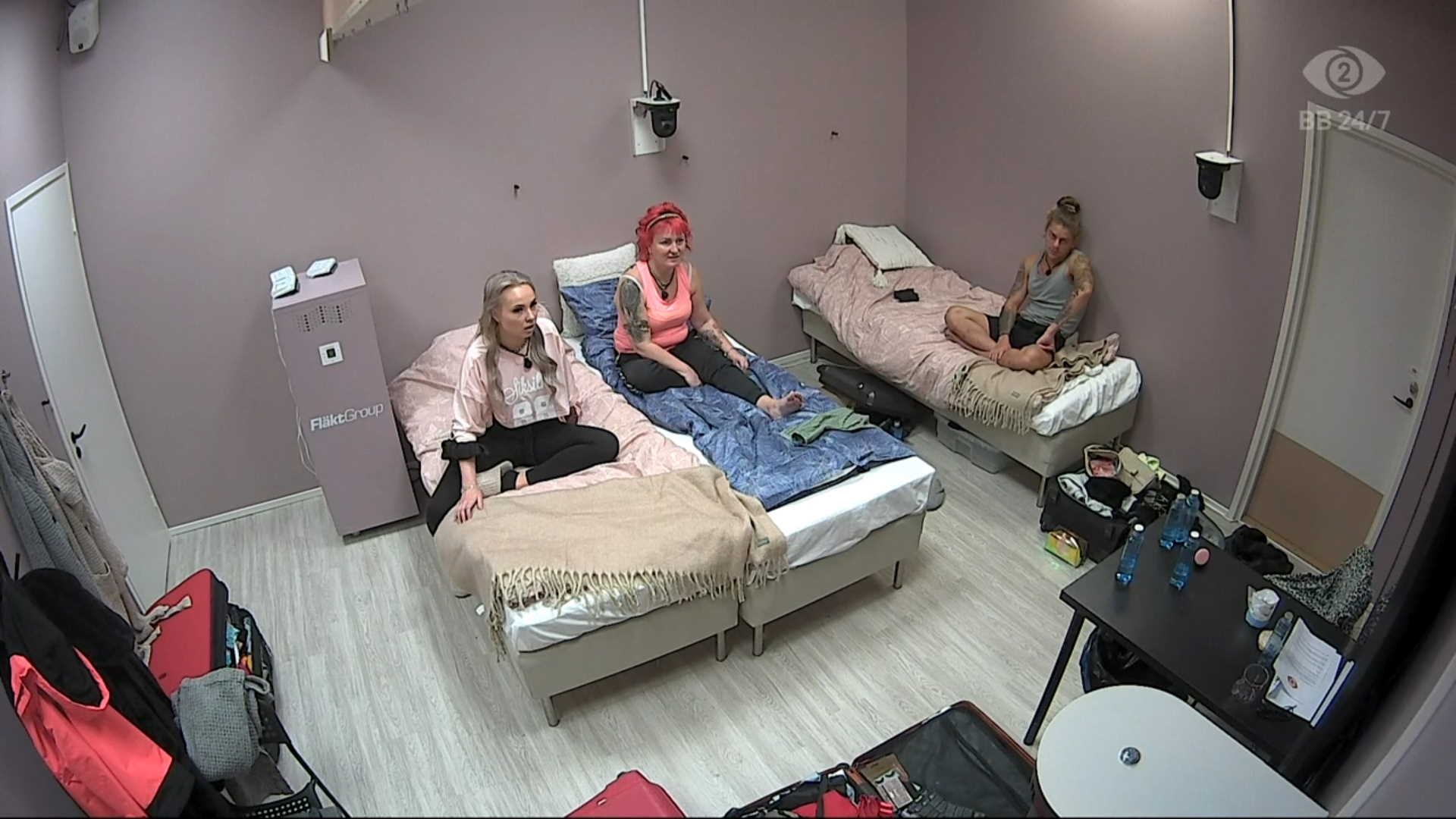 Noora, Maiju ja Samir seuraavat sviitissä talon tapahtumia televisiosta. Kuva: © Nelonen Media.